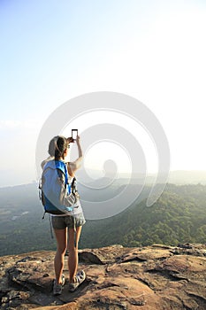 Woman photographer taking photos at mountain peak