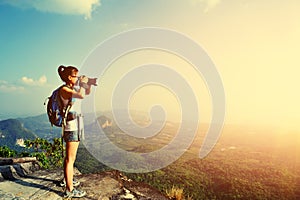 Woman photographer taking photos at mountain peak