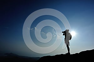 Woman photographer taking photos at mountain peak