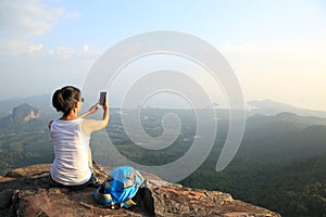 Woman photographer taking photos at mountain peak