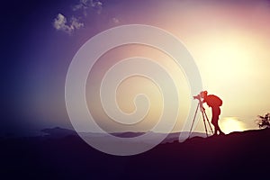 Woman photographer taking photos at mountain peak