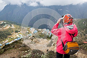 Woman photographer taking picture Namche Bazaar mountain village.