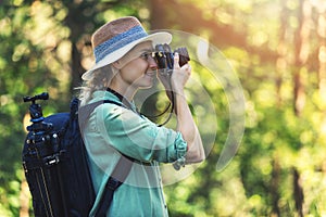 Woman photographer taking picture of nature with analog film camera in forest