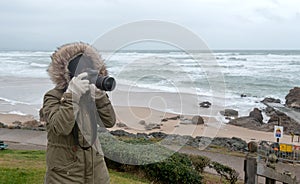 Woman photographer taking a picture at seaside in winter
