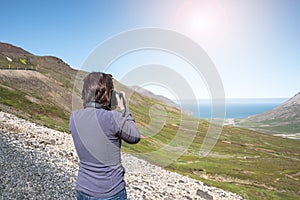 Woman taking photos of a wide valle in Iceland on a clear summer day photo