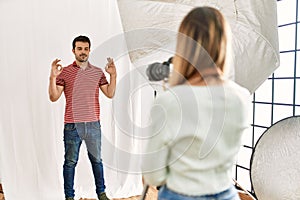 Woman photographer talking pictures of man posing as model at photography studio relax and smiling with eyes closed doing