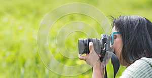 Woman photographer wear sunglasses and holding camera and take a