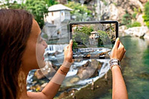 Woman photographing house on Buna spring in Blagaj