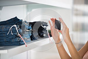 Woman Photographing Jeans In Retail Store