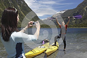 Woman Photographing Man Raise Oar At Mountain Lake