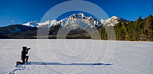 Woman photographing the Pyramid Mountain and the frozen Patricia Lake in the Jasper National Park Alberta, Canada