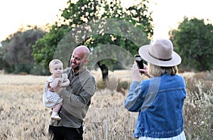 Woman photographs her husband with little daughter outdoor
