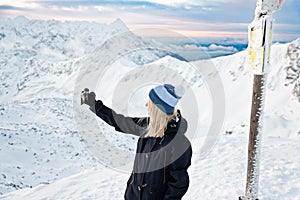 Woman photographs selphie on the Zawrat Pass in the Tatra Mountains in winter