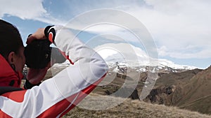 Woman photographs a snowy mountain