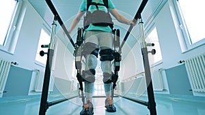 A woman with physical disability is walking in the exoskeleton
