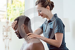 Woman physical therapist massaging young black man