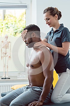 Woman physical therapist massaging young black man