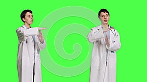 Woman physician doing timeout gesture against greenscreen backdrop