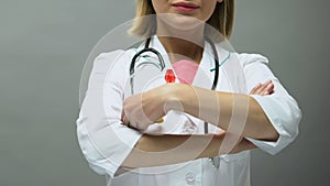 Woman physician with red ribbon posing for camera, AIDS awareness, sti disease