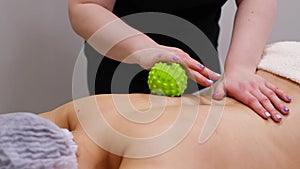 Woman at the physiotherapy receiving ball massage from therapist. A chiropractor heals the patient& x27;s back in medical