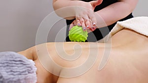 Woman at the physiotherapy receiving ball massage from therapist. A chiropractor heals the patient& x27;s back in medical