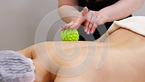 Woman at the physiotherapy receiving ball massage from therapist. A chiropractor heals the patient& x27;s back in medical