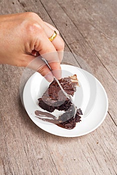 Woman pick homemade brownies on white plate. With chocolate fudg