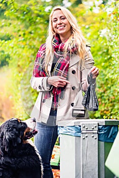 Woman is picking up dog poo putting it in dustbin photo