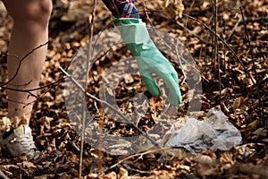 Woman picking up dump on dirty forest