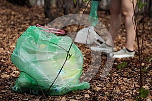 Woman picking up dump on dirty forest