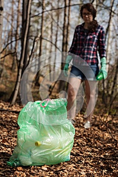 Woman picking up dump on dirty forest