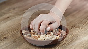 Woman Picks Up a single Cashew, To Eat, From Her Bowl. took a nut on the left side