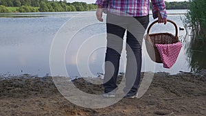 Woman with picnic basket looks out onto lake