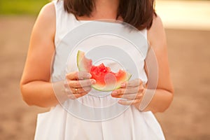 Woman with a piece of ripe watermelon in a hand in a picnic. Summer picnic. Vacation concept