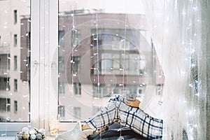 Woman in pijamas sitting on windowsill with a cup of coffee. Winter mood.