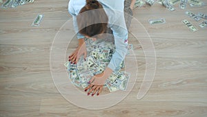 Woman piles as many US dollar bills as possible on the floor