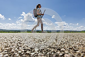 Woman with pilgrim stick and backpack barefoot on a road