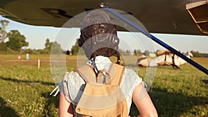 Woman pilot portrait walking to her small airplane at summer sunny weather. Active female flier doing sport. Aircraft