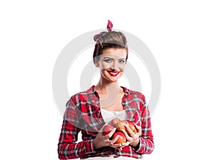 Woman, pin-up hairstyle holding armful of apples. Autumn harve