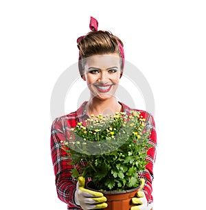 Woman with pin-up hairstyle holding flower pot with yellow daisies