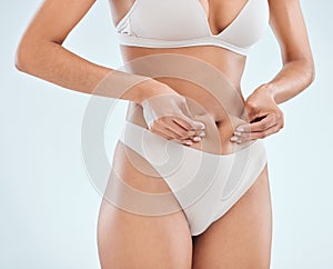 Woman, pinch abdomen and underwear in studio, detox and results of aesthetic on white background. Female person