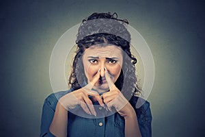 Woman pinches nose with fingers looks with disgust something stinks bad smell photo