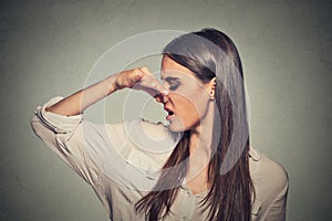 Woman pinches nose looks with disgust something stinks bad smell photo