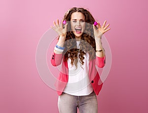 Woman on pink background showing heart shaped chocolate candies