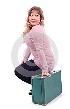 Woman in pink blouse sits on suitcase