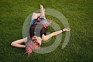 Woman with pink dreadlocks resting on the grass