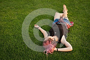 Woman with pink dreadlocks resting on the grass