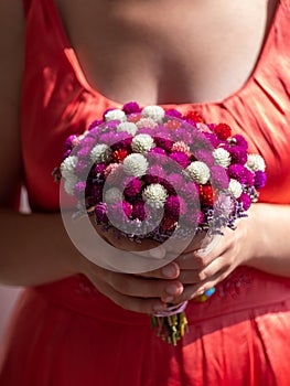 Woman in pink dress holding bridal bouquet in hands close-up. Wedding purple red white flowers bunch.Wedding decorations