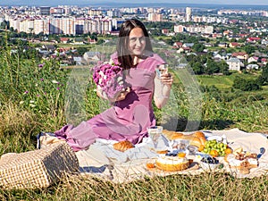 A woman in pink dress sits on a picnic in a park with panoramic view