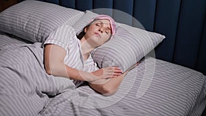 woman in a pink eye mask lies under a blanket in a bed and suffers from insomnia.